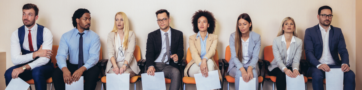 Professzionális megjelenésű álláskeresők, kezükben papírokkal, várakoznak egy állásinterjúra.